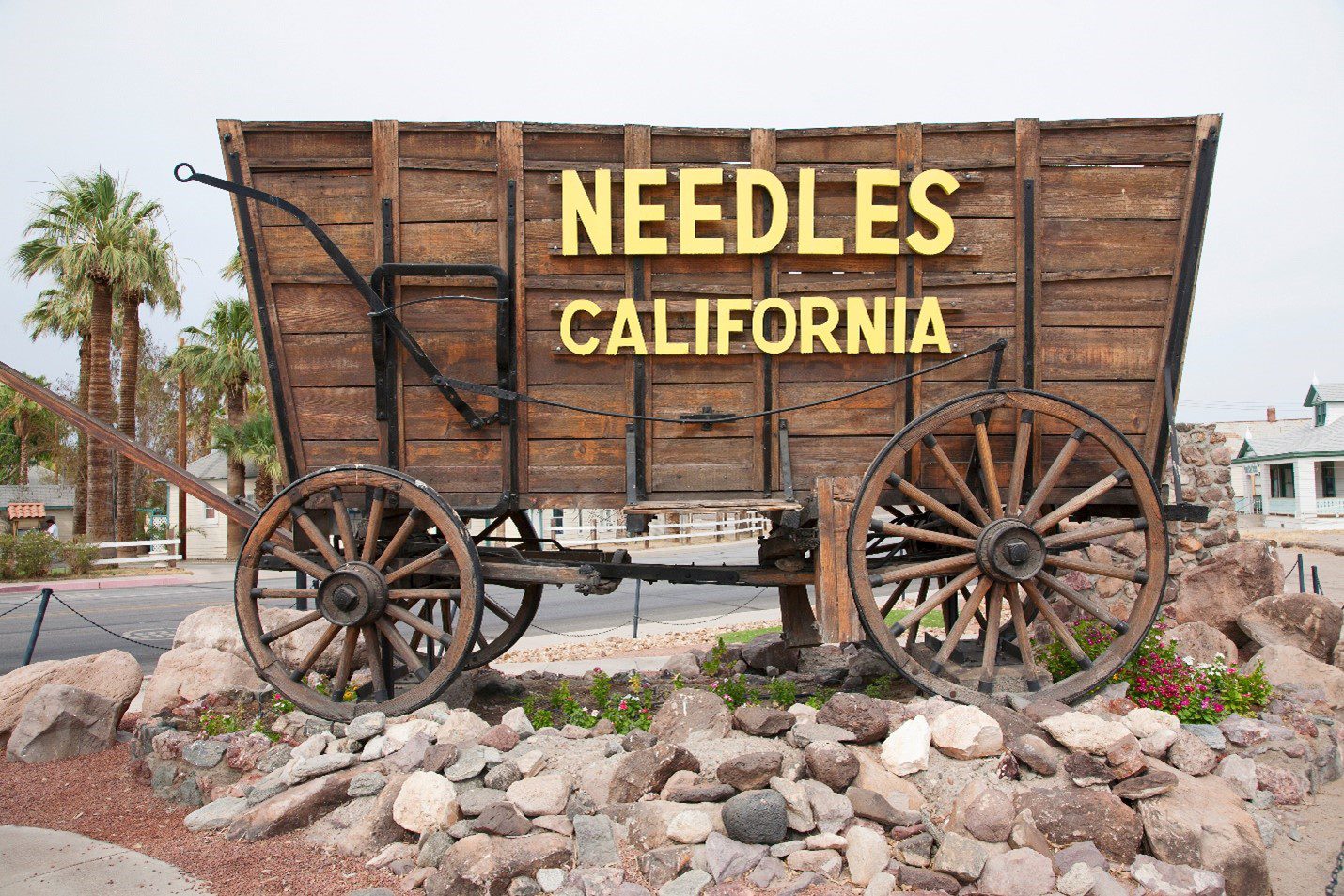 A wooden wagon with large wheels and text that says 'Needles California' in large letters.