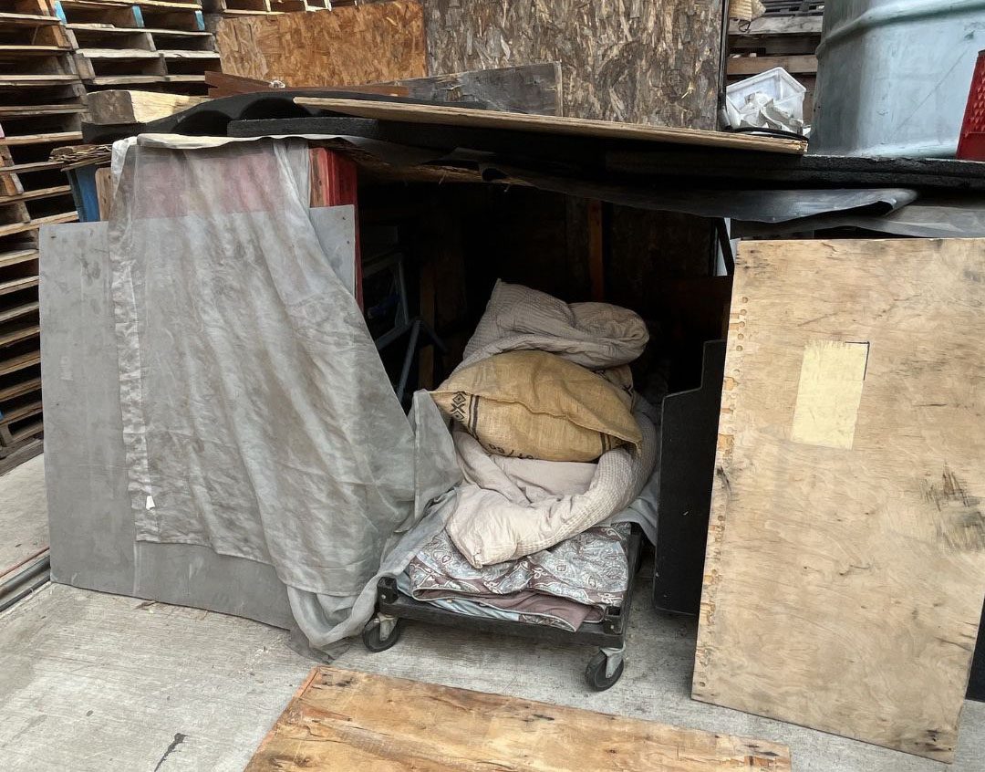 A makeshift living enclosure constructed within the pallet yard.