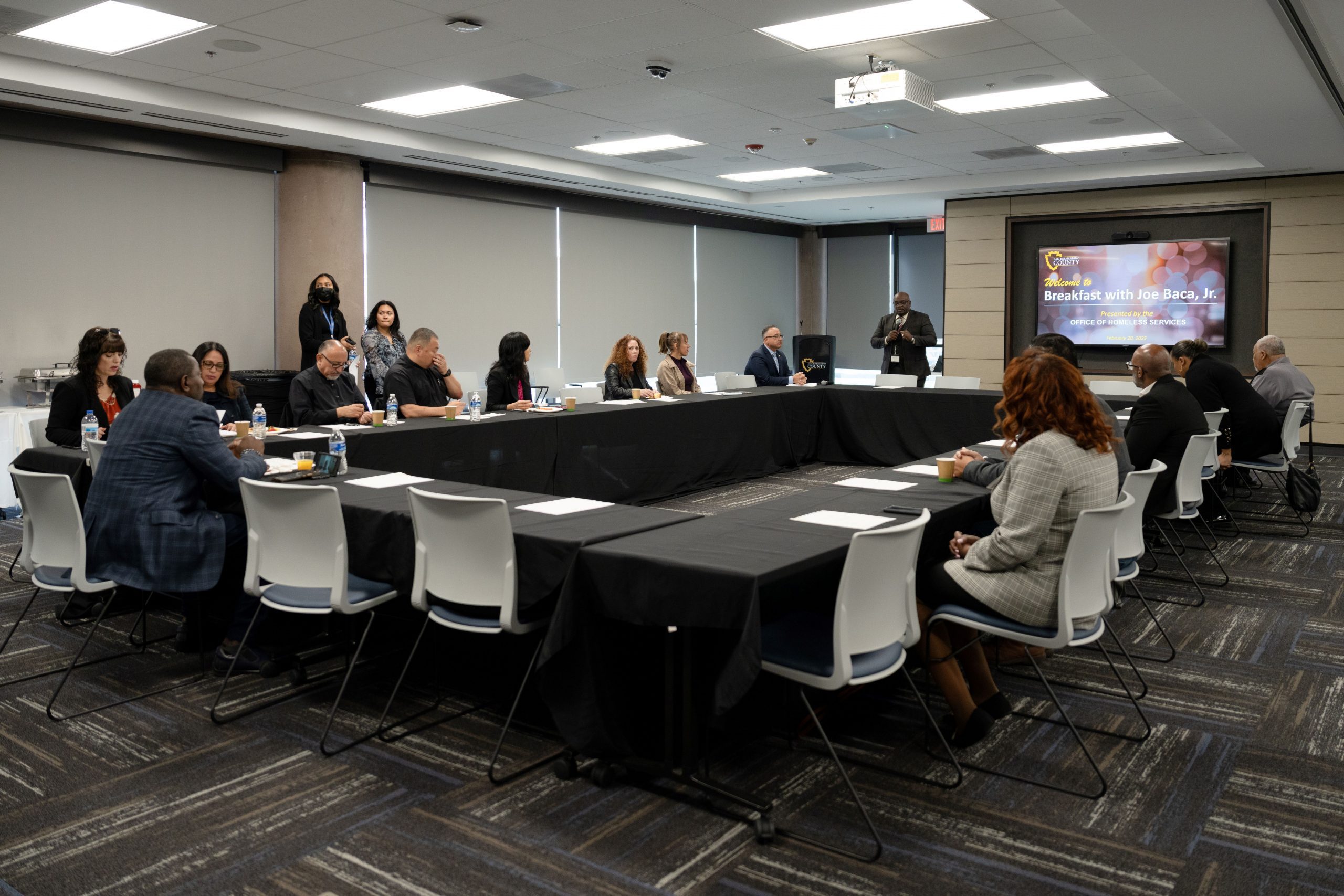 OHS Chief Marcus Dillard stands at the front of a conference room, providing an update to attendees at the homelessness roundtable.