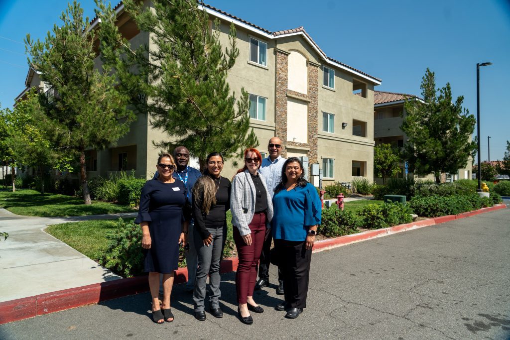 A group of people standing on a street in front of an apartment building.
