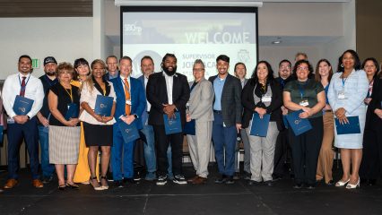 A group of people standing on a stage holding certificates and smiling.