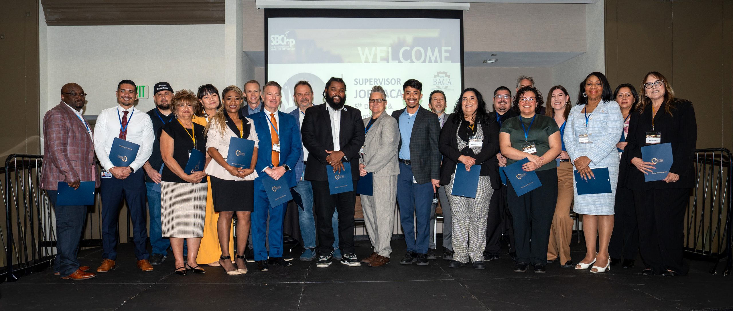 A group of people standing on a stage holding certificates and smiling.