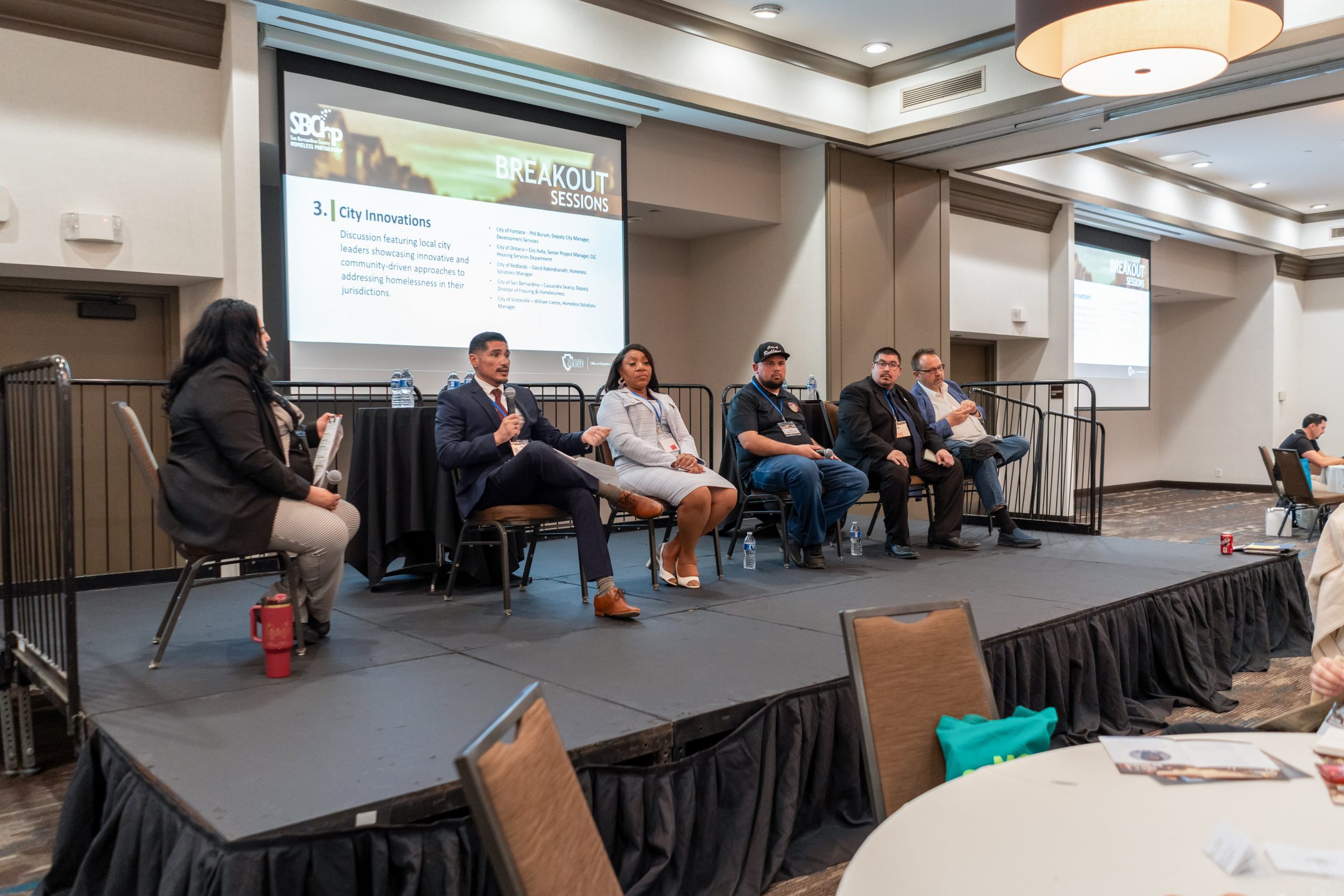 Six people are on stage with one person speaking from a mic.