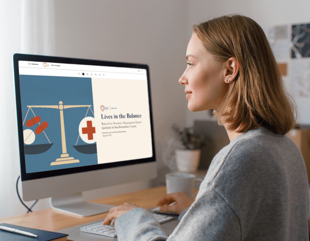 Woman working at a computer displaying the Lives in the Balance opioid data StoryMap.