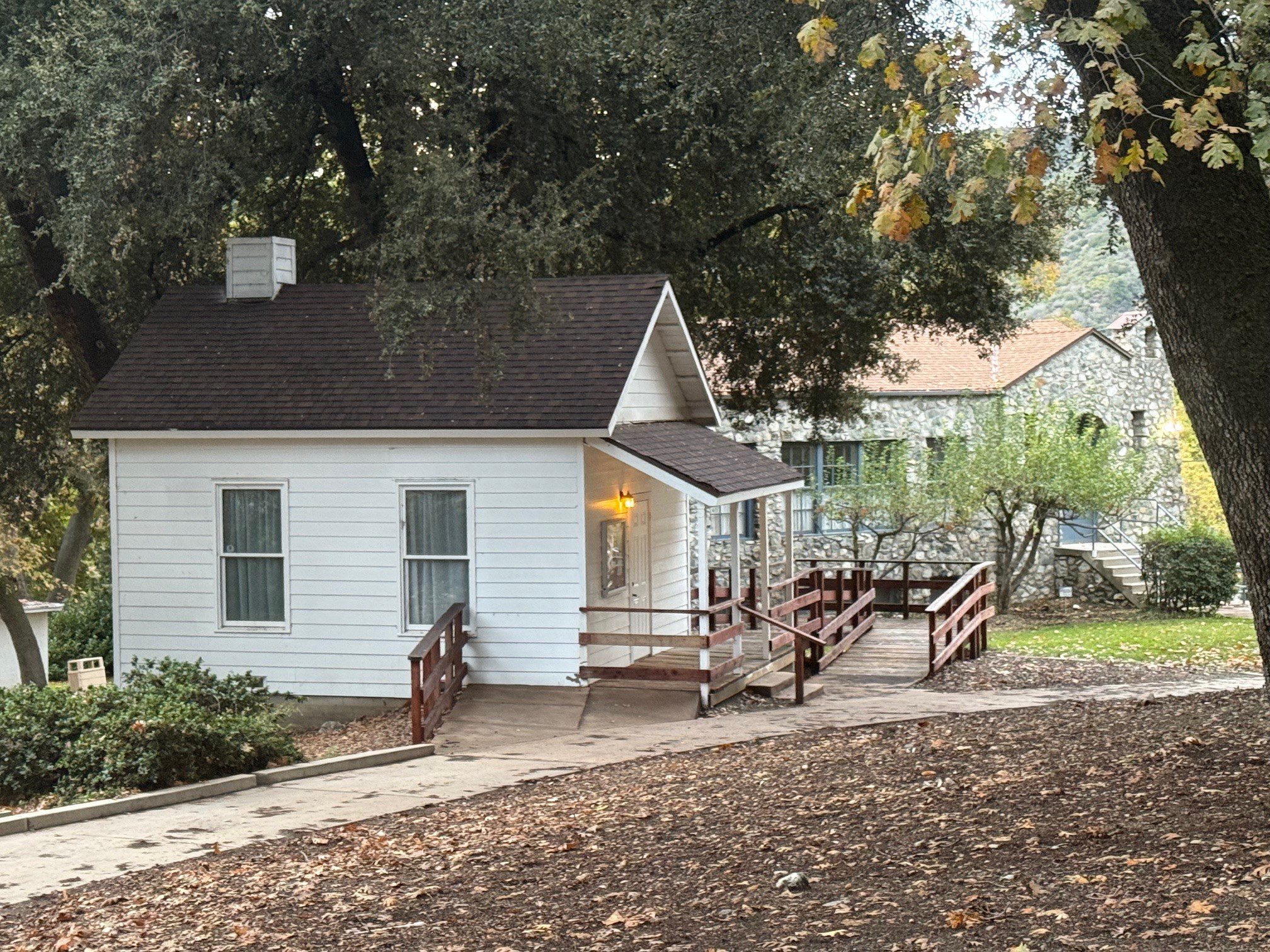 A side view of a small white house with a ramp leading up to the front porch.