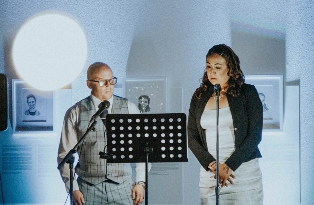 A man and woman standing at a podium reciting poetry.