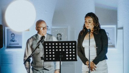 A man and woman standing at a podium reciting poetry.