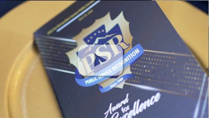 Program with text: PSR, PUBLIC SERVICE RECOGNITION, Since1989, & Award for Excellence” on a plate with video play button overlay.