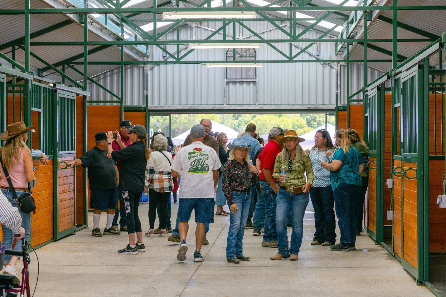 A group of people inside a barn with two women dressed in Western attire stare into the camera.