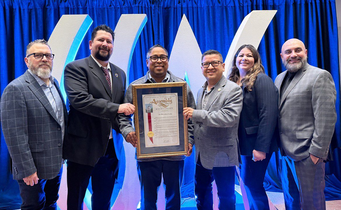 Michael Stoffel, Leonardo Gonzalez, Jeff Gonzalez, Jesse Armendarez, Gina King, and Jose Mancilla stand together holding a framed California State Assembly resolution at CSAC award ceremony.