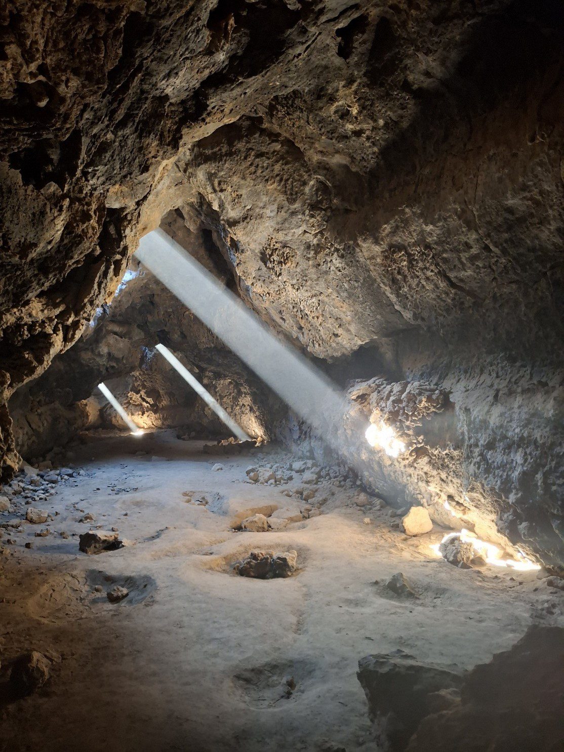 A cave with sunlight shining through small openings.
