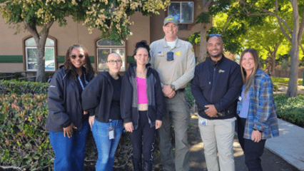 A group of six people are standing outdoors in front of a building.