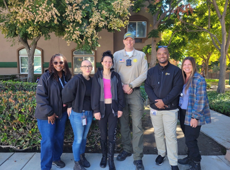 A group of six people are standing outdoors in front of a building.