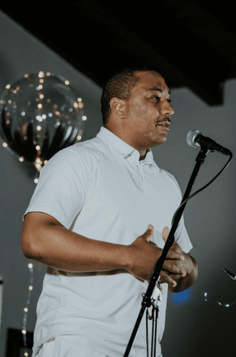 A young man stands a mic reciting a poem.