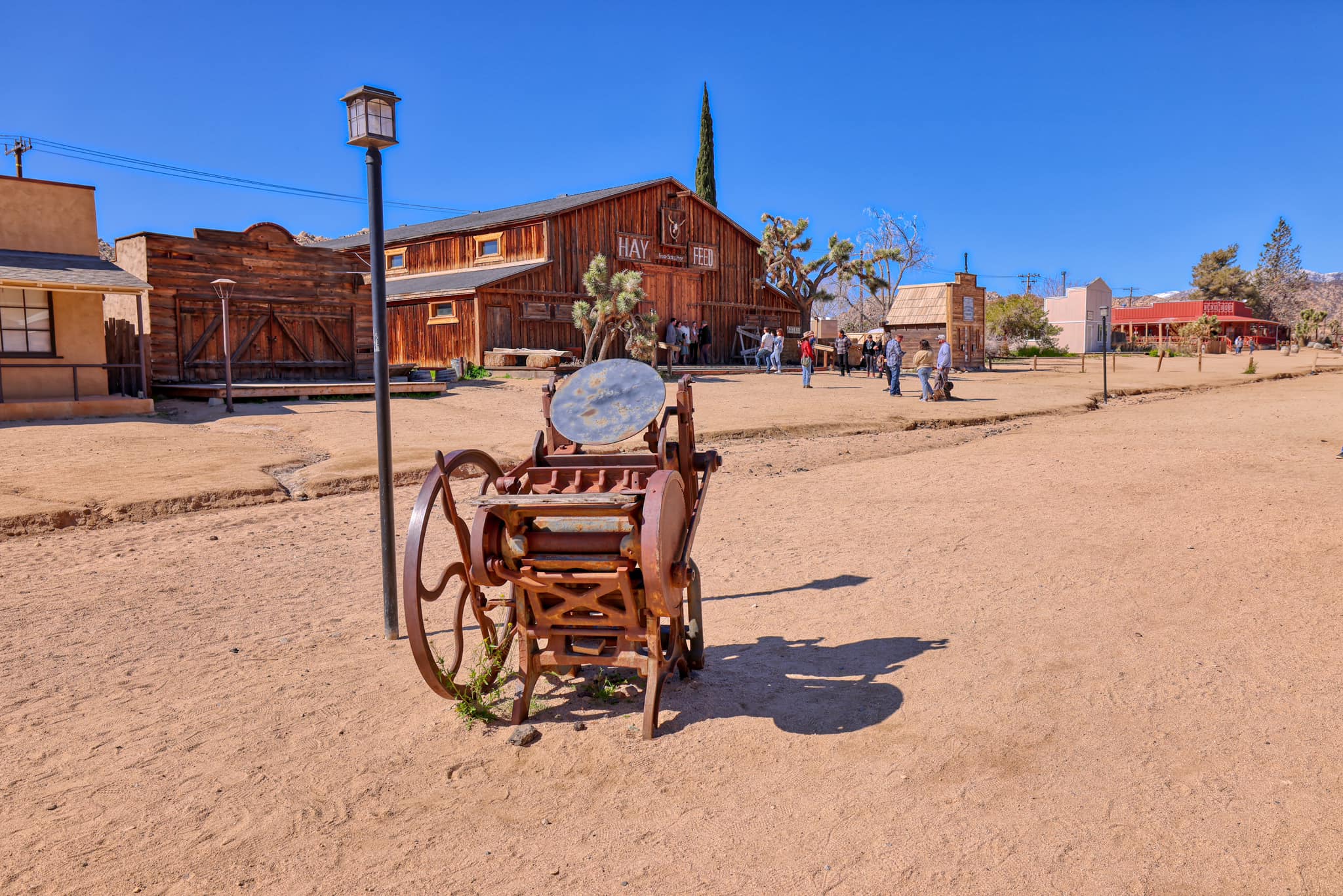 A vintage washing machine in the foreground and rustic wooden buildings in the background. Also visible is several visitors
