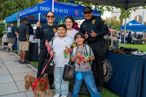 Two SBC Probation officers pose with a family at a community outreach booth.