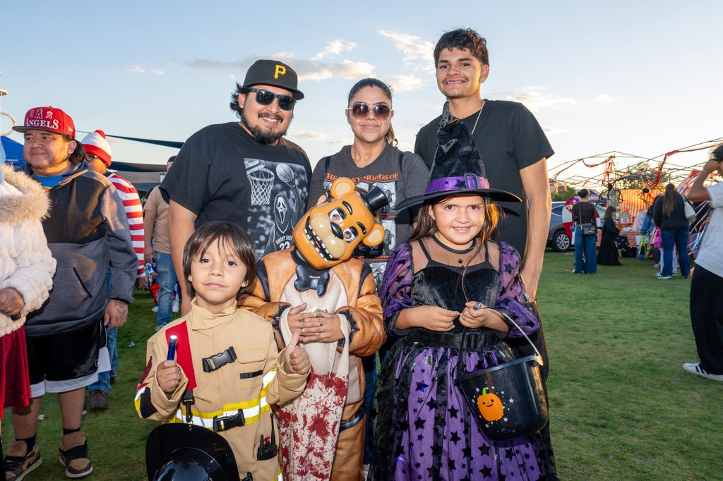 Family poses together in Halloween costumes during a community trick-or-treat event at Ayala Park.