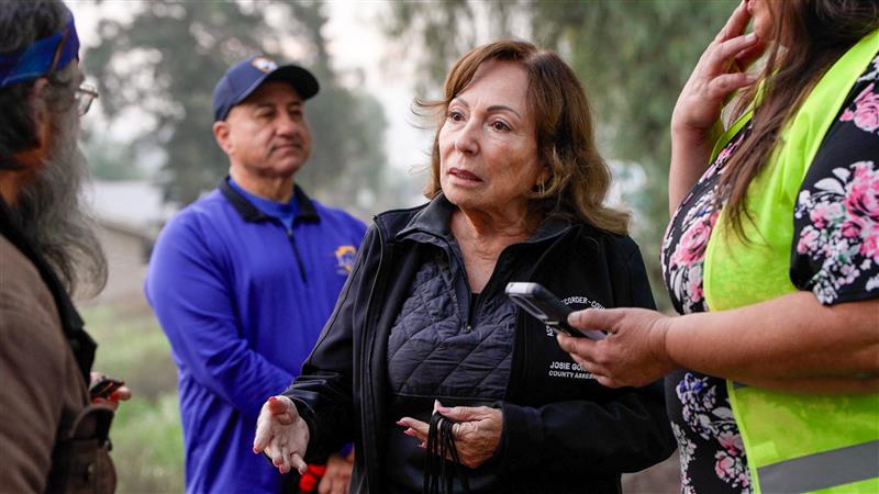 Two other individuals are visible in the background.