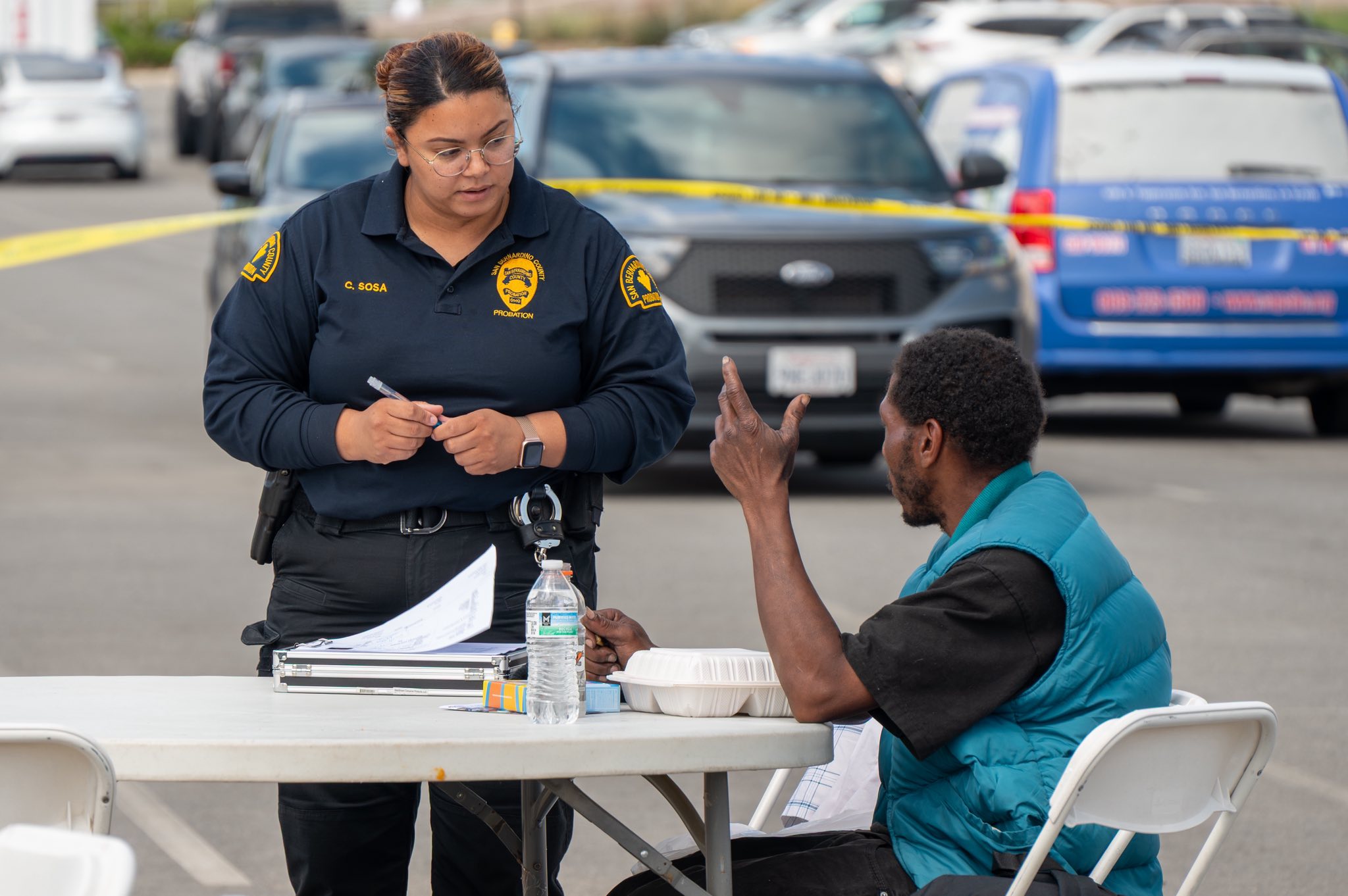 Probation officer speaks with a community member at an outreach table, providing information and resources.