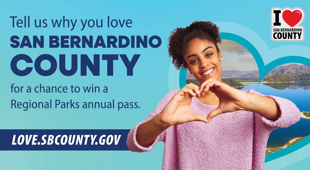 A graphic of a smiling woman making a heart shape with her hands with a view of a lake in the background. Text invites participation in a contest to win a Regional Parks annual pass. Also visible is love.sbcounty.gov.