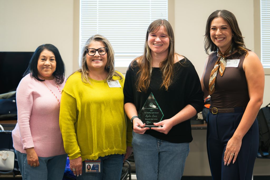 Four women smile for a photo, with teacher Lydia Lane holding the Guiding Light Award.