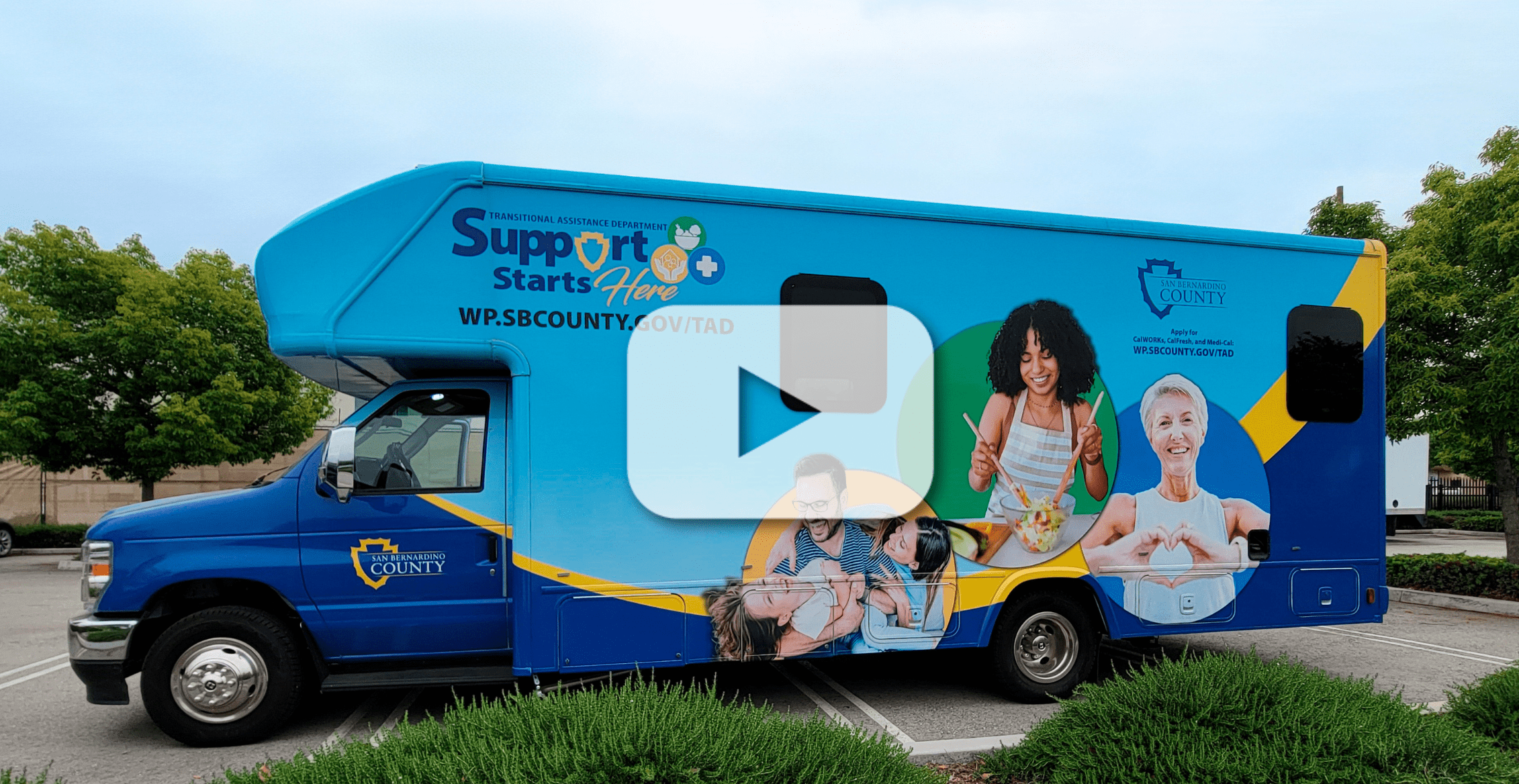 Parked Mobile Office with text, Support Starts Here, wp.sbcounty.gov/TAD and County logo. Images of dad and kids, woman cooking and senior with heart.