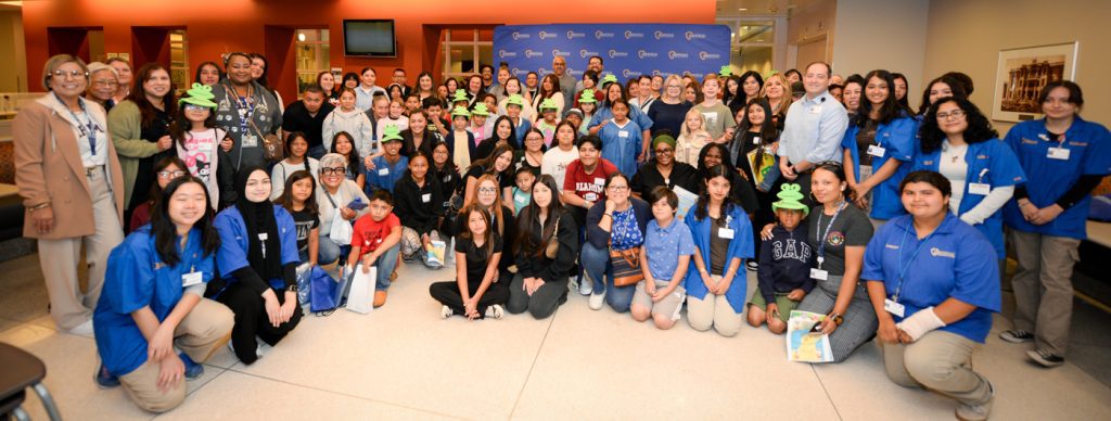 Group of ARMC staff and children pose together during Take Your Child to Work Day, celebrating a day of learning and hands-on hospital tours.