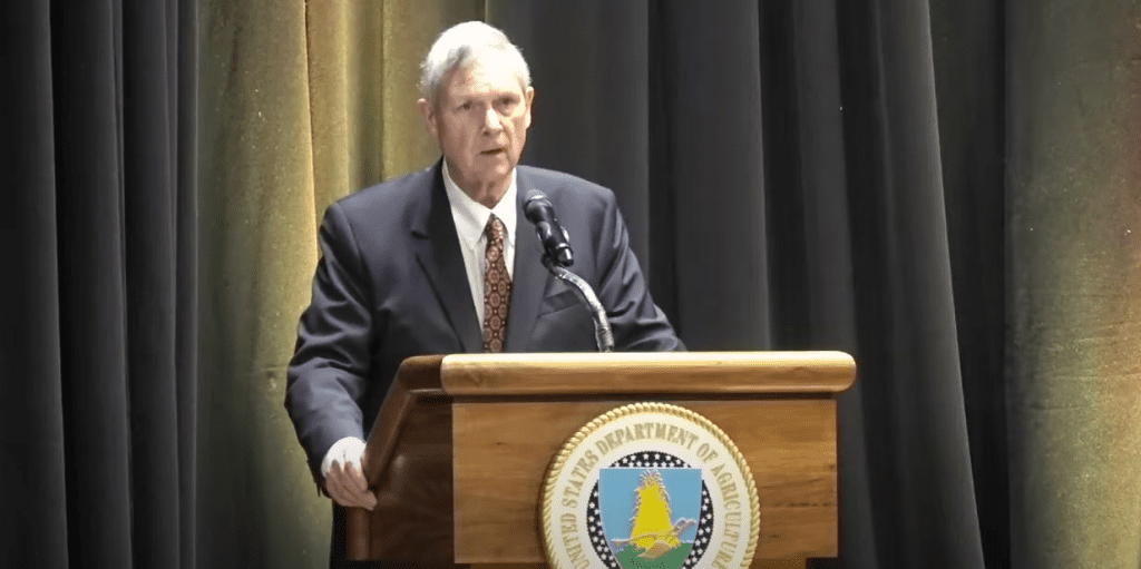 United States Secretary of Agriculture Tom Vilsack stands at a podium.