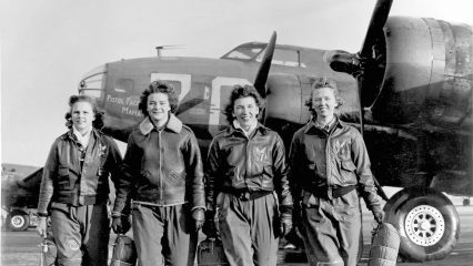 Four women in flight suits stand in front of an aircraft.