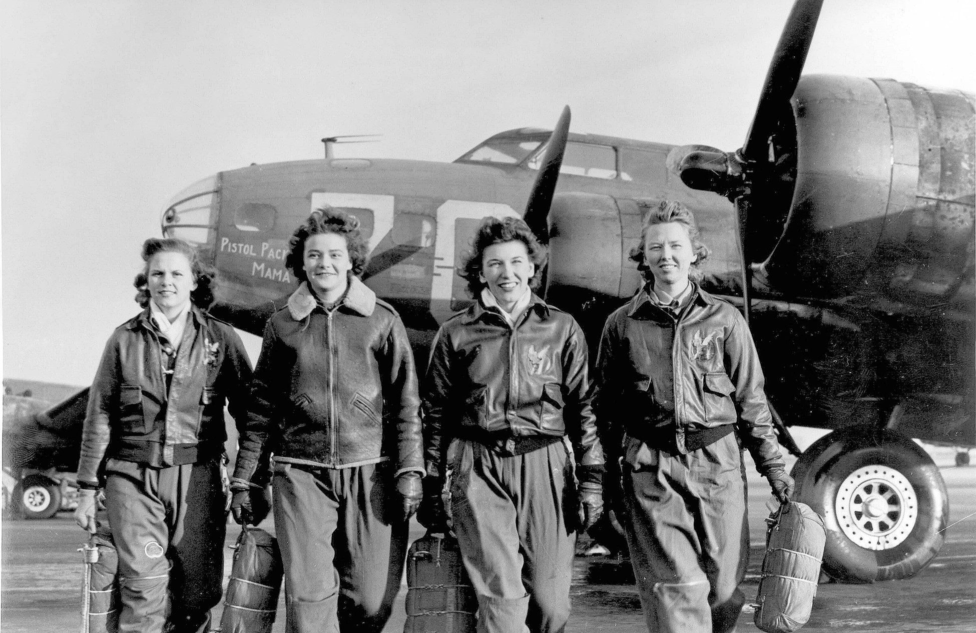 Four women in flight suits stand in front of an aircraft.