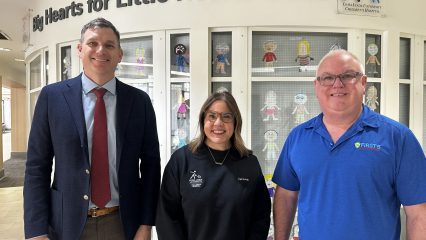 First 5 San Bernardino and Loma Linda University Children’s Hospital staff pose in front of an indoor display of colorfully decorated paper dolls.