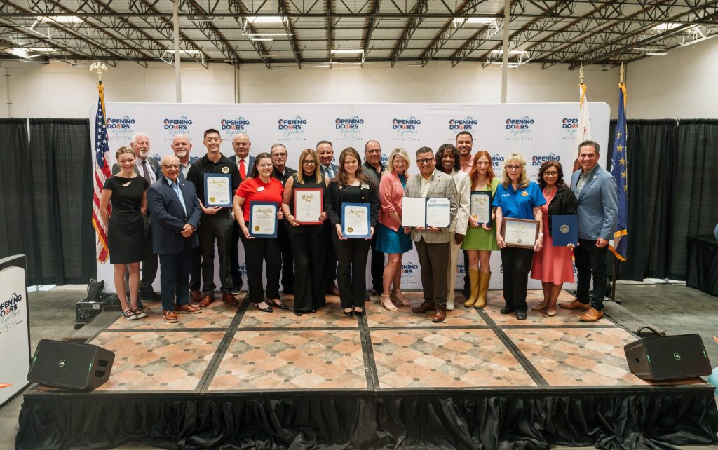 A group of individuals standing on a stage holding certificates.