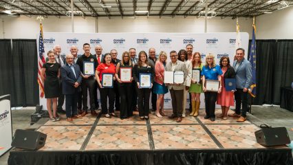 A group of individuals standing on a stage holding certificates.