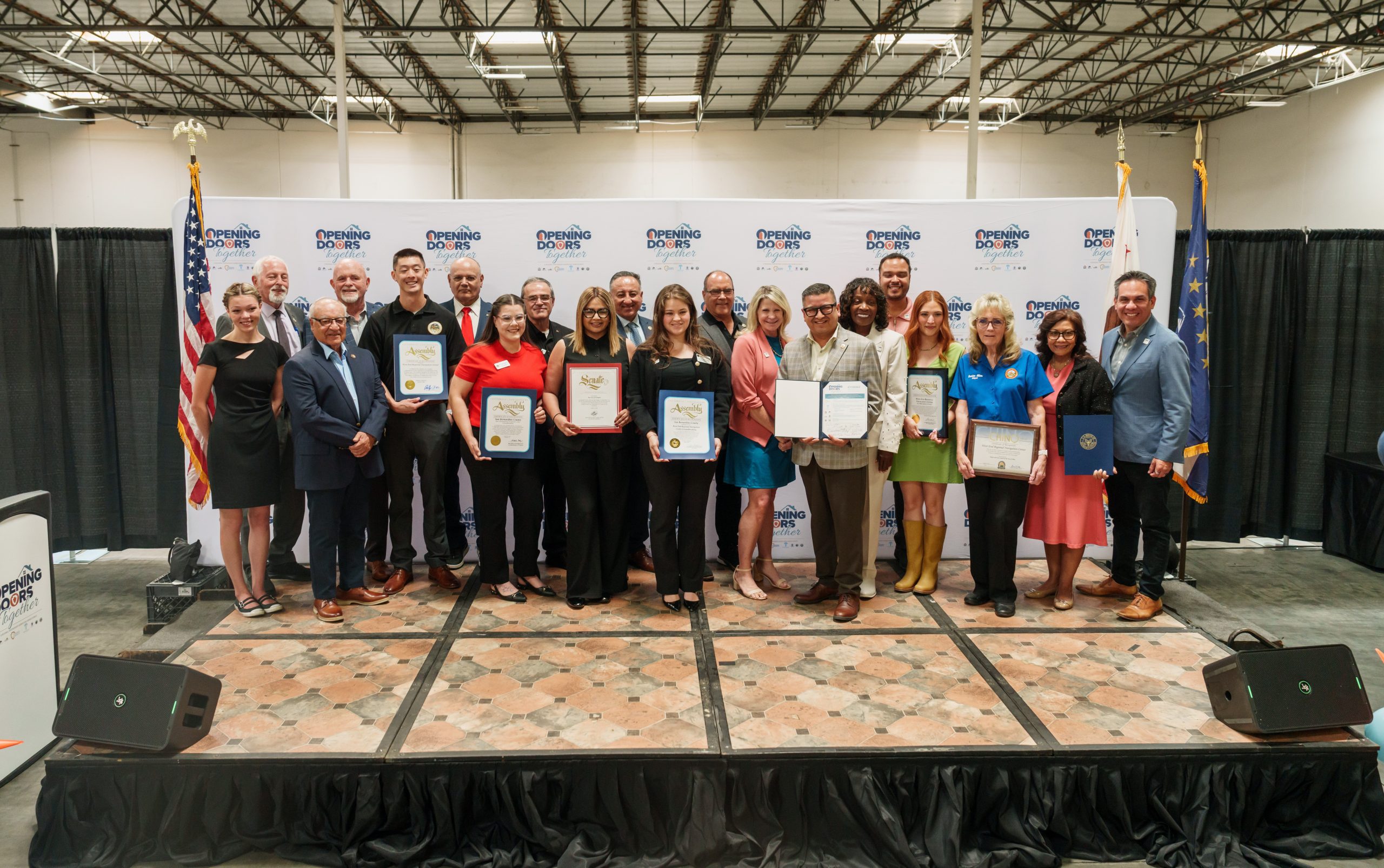 A group of individuals standing on a stage holding certificates.