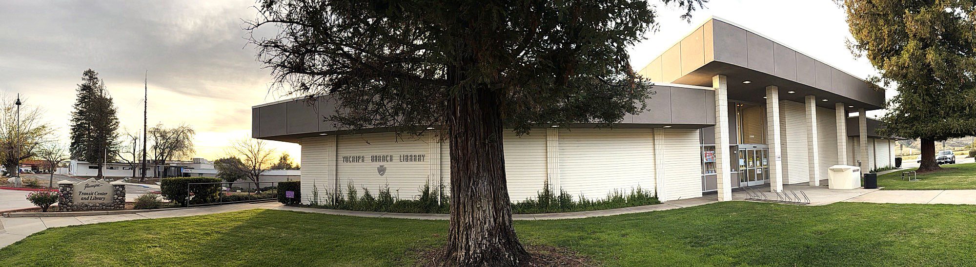 A beige building with a tall clock tower stands under a clear blue sky. Two flags are in front. The scene is calm and orderly, conveying a civic atmosphere.