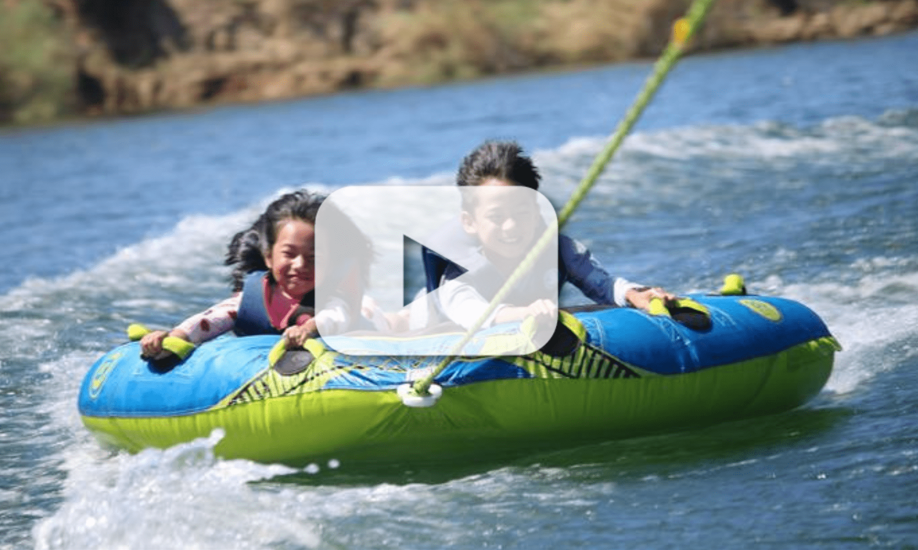 Two young children have fun on a green and blue raft in the water.