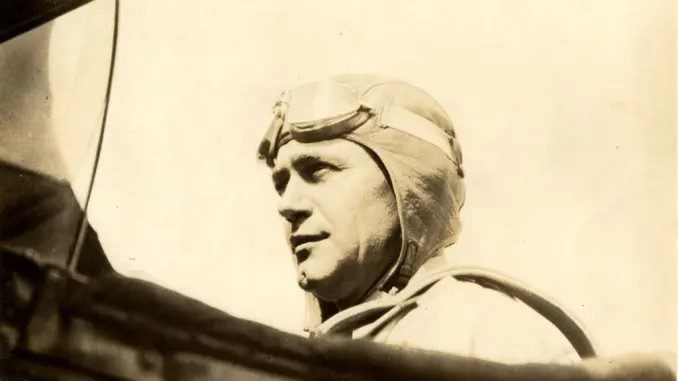 Historic photo of an Air Force pilot wearing his uniform and sitting in a plane.