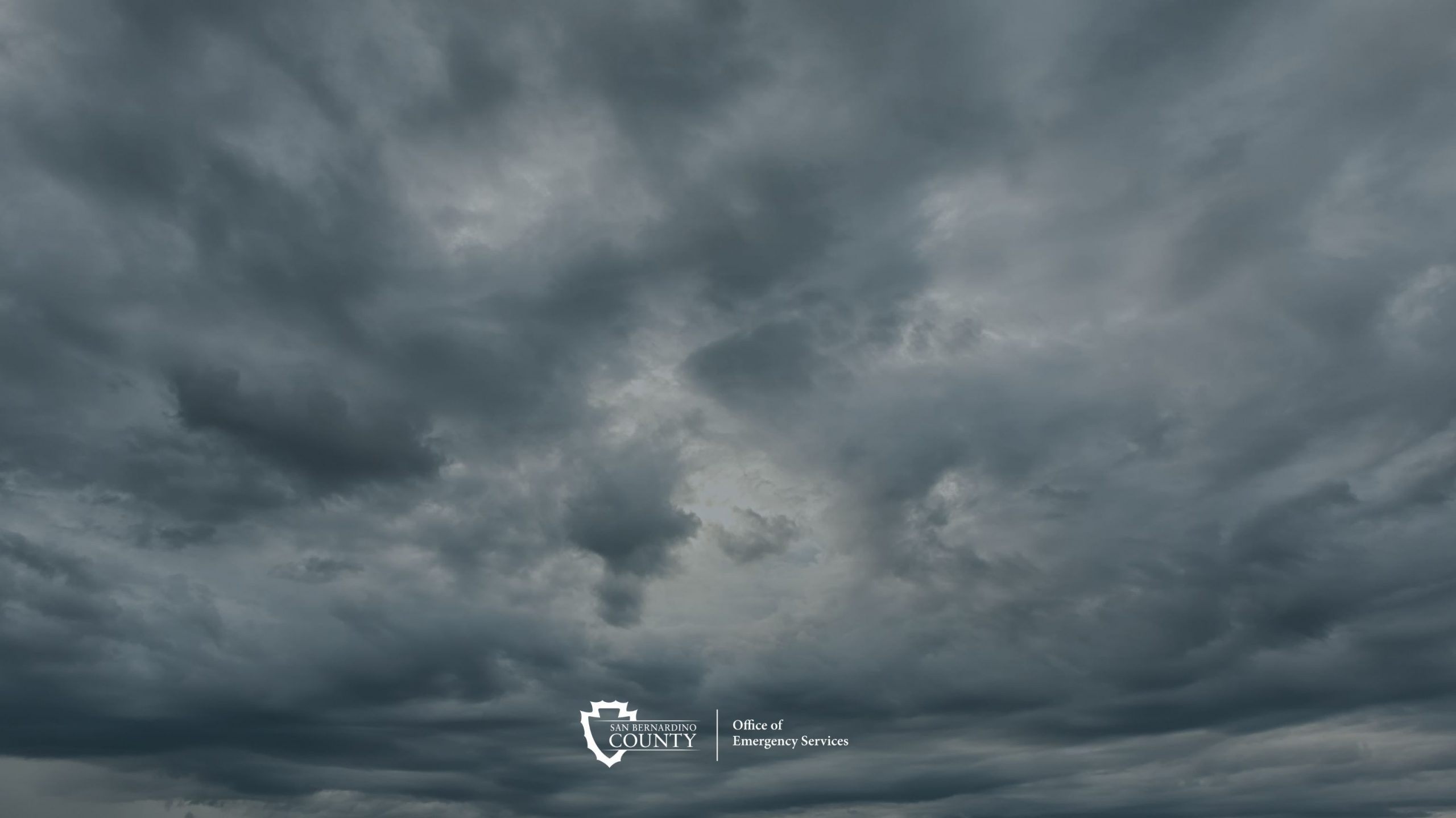Dark storm clouds, with the San Bernardino County Office of Emergency Services logo.