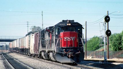 A freight train travels along a railway line pulling several cargo containers.