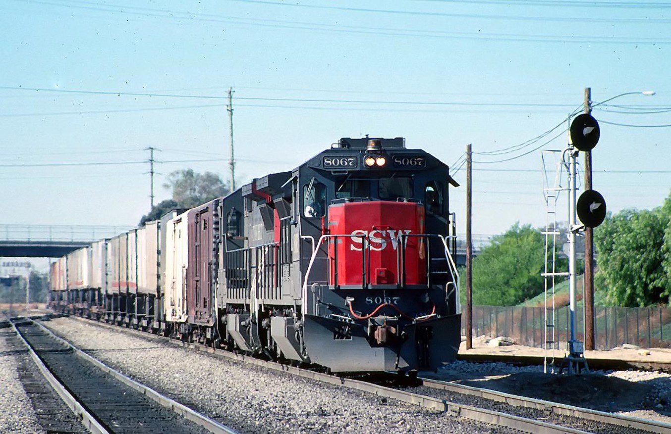 A freight train travels along a railway line pulling several cargo containers.