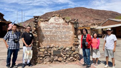 Five people gather around a large plaque surrounded by stones at Calico Ghost Town.