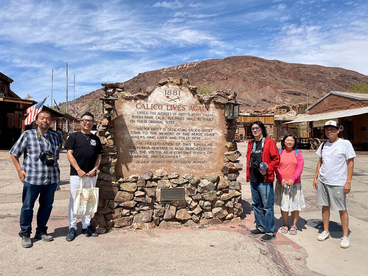 Five people gather around a large plaque surrounded by stones at Calico Ghost Town.