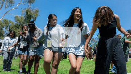 Video thumbnail showing teens participating in an outdoor team‑building activity with a play button overlay.