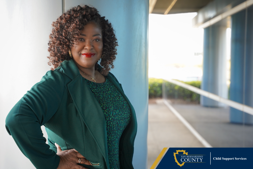 A woman standing outside near a pillar and window, with shrubs in the background and the Child Support Services logo in a blue and gold box.