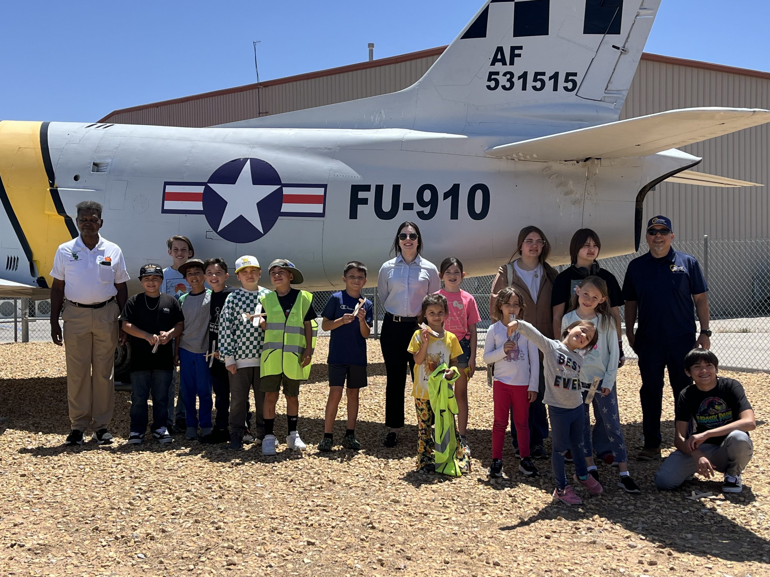 Group of students and adults posing in front of a vintage jet.