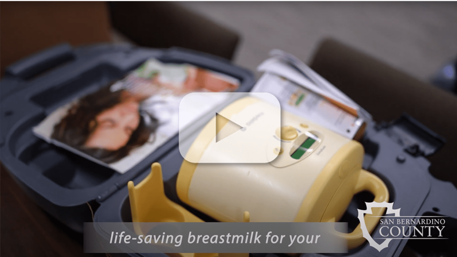 Medela breast pump kit in open case with overlaid play button for San Bernardino County WIC loan program video.