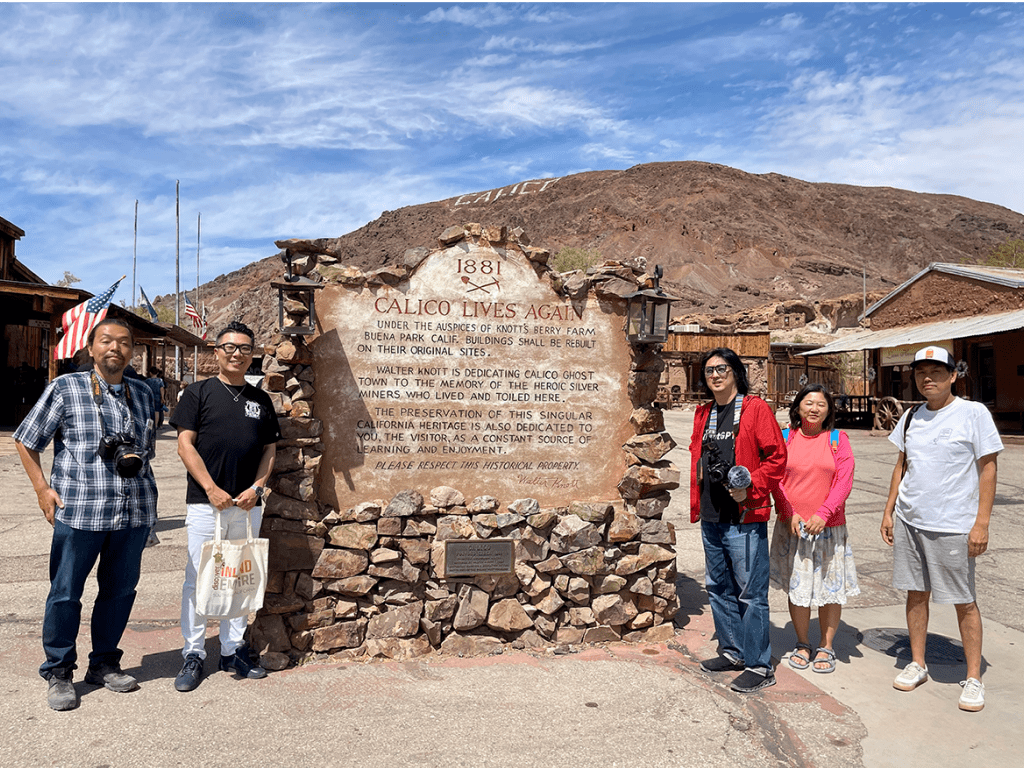 Five people gather around a large plaque surrounded by stones at Calico Ghost Town.