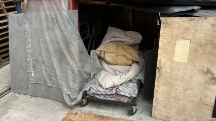 A makeshift living enclosure constructed within the pallet yard.