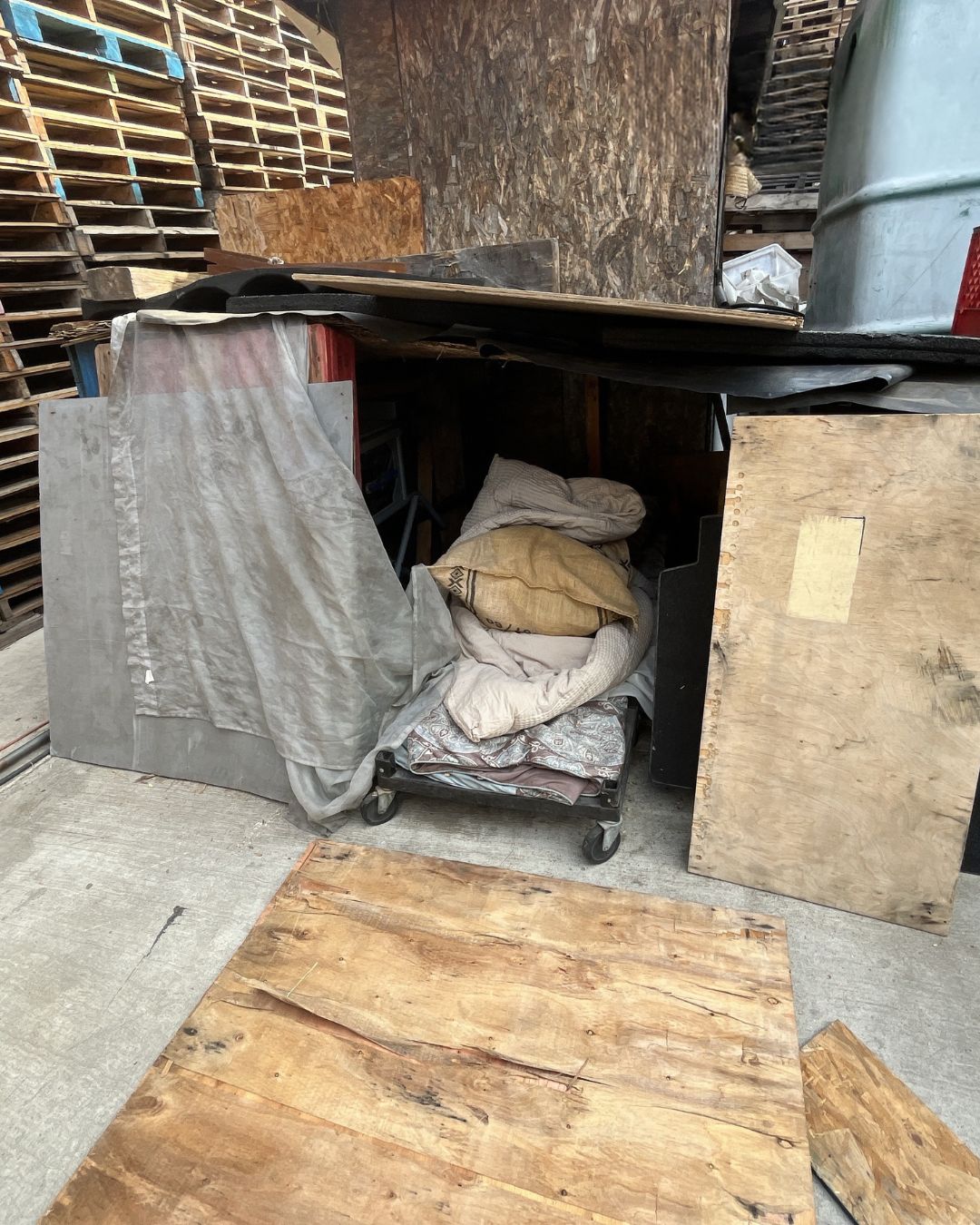 A makeshift living enclosure constructed within the pallet yard.