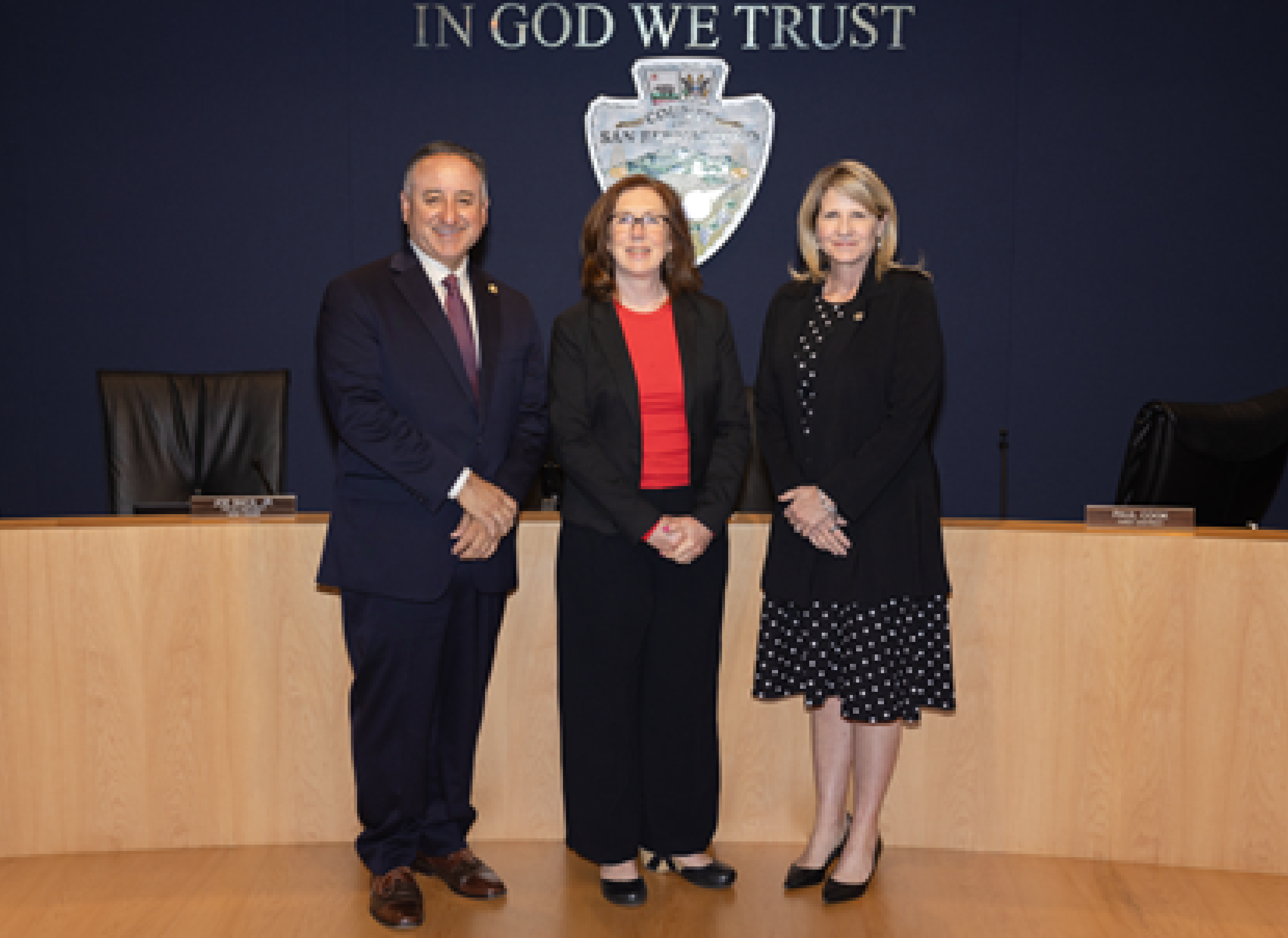 Baca, Jr., Decker, and Rowe pose in the Government Center’s Covington Chambers, standing in front of the county seal.